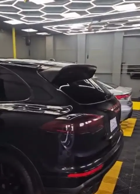 The work bay: hexagon ceiling lights over a black and yellow tiled floor, a black SUV inside