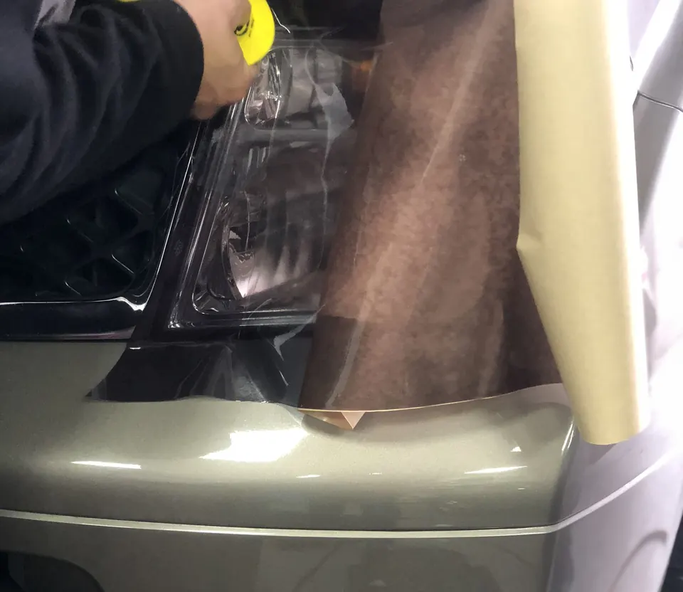 Film being heated and laid over a headlight