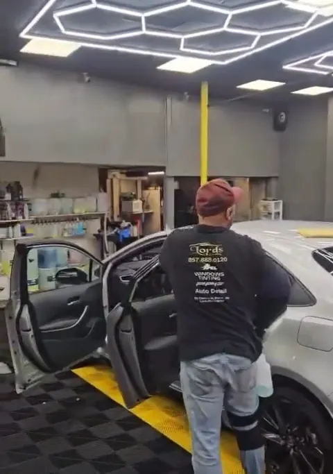 A Lords Detailing installer working on a car door in the bay