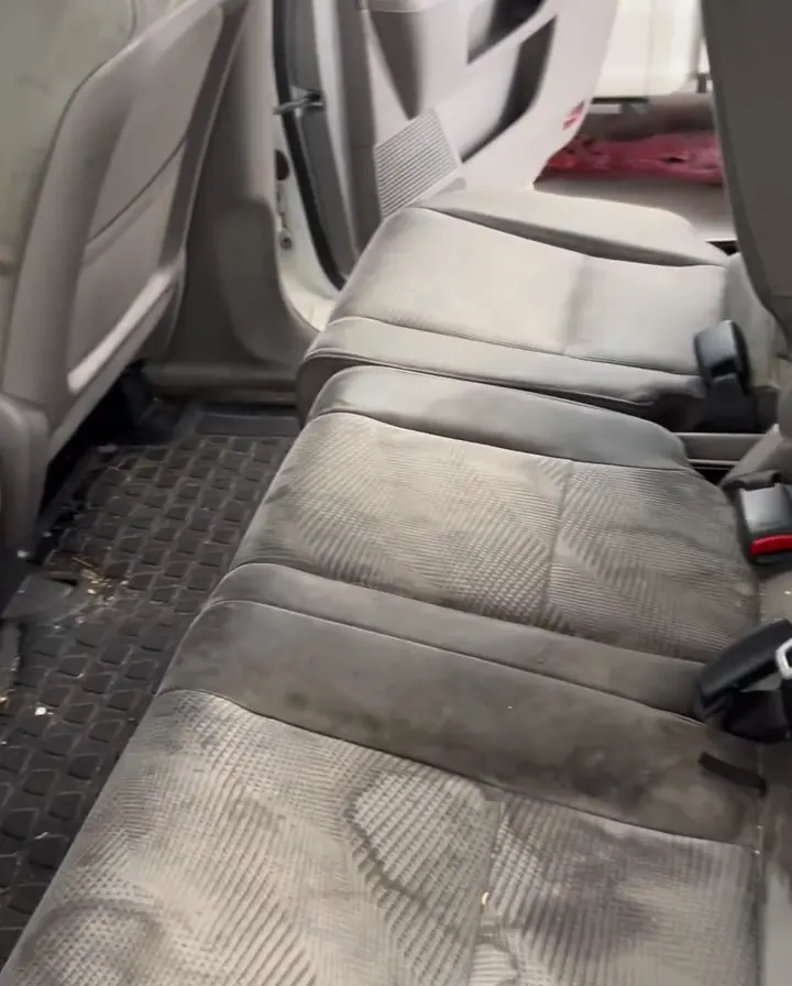 Banco de trás de um Honda Pilot antes do detalhamento: tecido manchado e tapete sujo