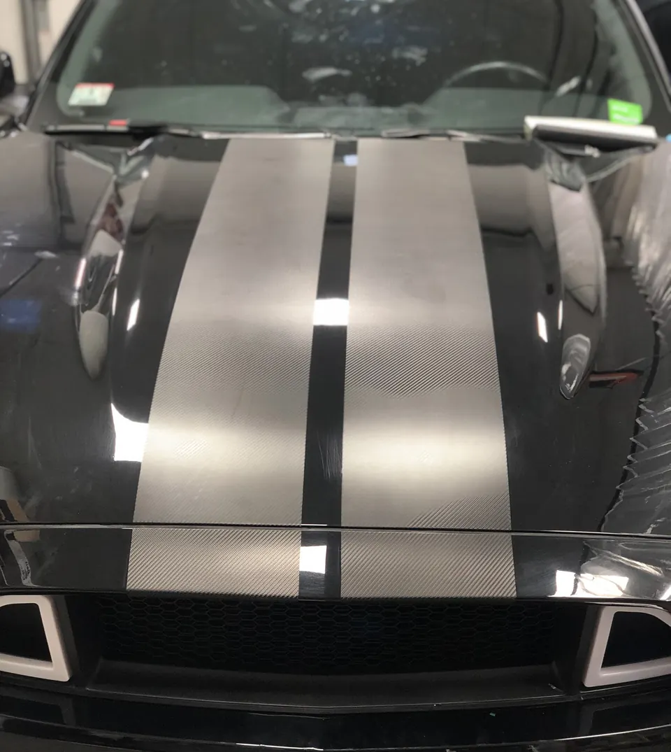 Black Mustang with two brushed silver vinyl stripes over the hood